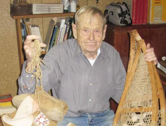 John Macfie holding snowshoes, mukluks and mitts